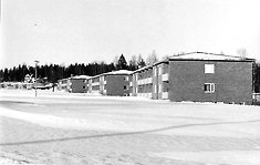 En svartvit vinterbild med tre tvåvåningshus.