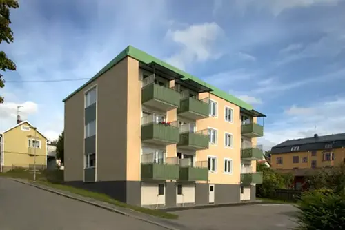 Ett gult stenhus i tre våningar med gröna balkonger.