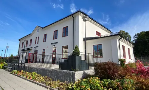 Vitt putsat stationshus med röda dörrparier.
